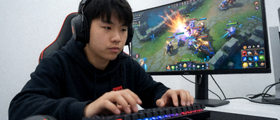 DOTA2职业选手在比赛中专注操作，手速飞快，显示器上显示激烈的团战画面