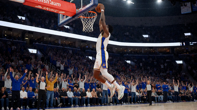 NBA比赛中球员起跳扣篮的瞬间，篮球场上灯光璀璨，观众席上人声鼎沸